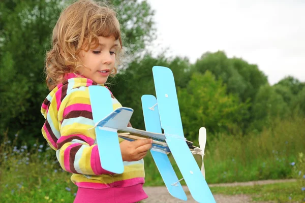 Kleines Mädchen mit Spielzeugflugzeug in den Händen im Freien — Stockfoto