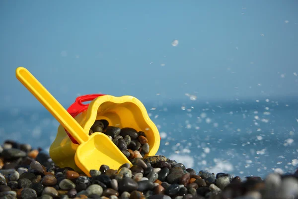 Gelber Kindereimer mit Schaufel am Meeresufer — Stockfoto