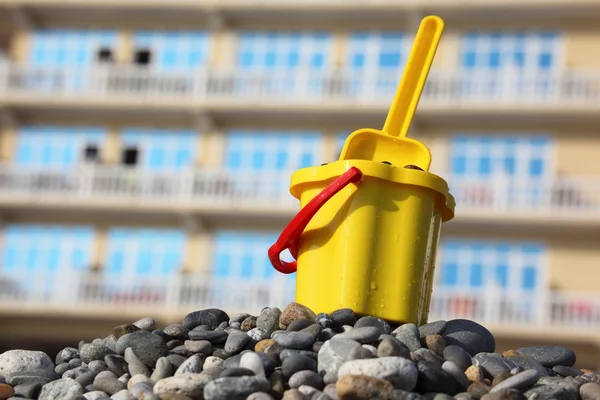 Cubo para niños amarillo con cuchara en guijarro —  Fotos de Stock