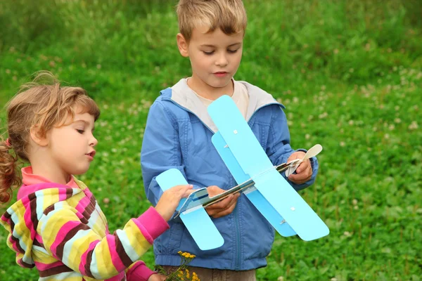 Niña y niño con juguete avión en manos al aire libre — Foto de Stock