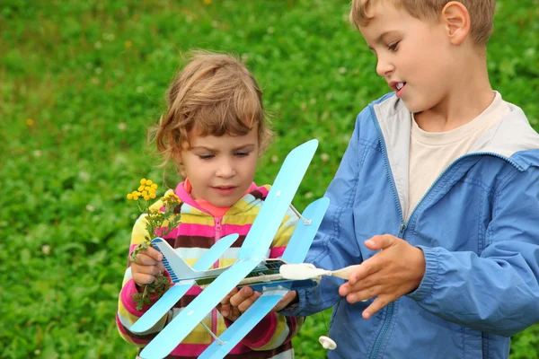 Niña y niño con juguete avión en manos al aire libre — Foto de Stock