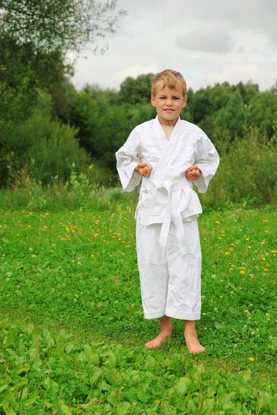 Karate pojke står på gräsmattan — Stockfoto