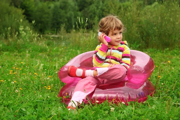 Şişme koltuk l üzerinde oyuncak telefon görüşmeleri küçük kız oturuyor — Stok fotoğraf