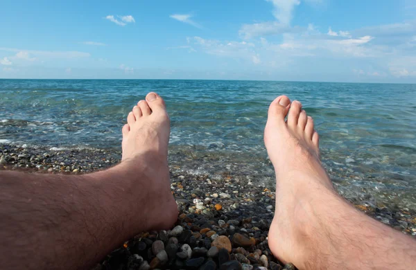 Две ноги на брусчатом пляже — стоковое фото