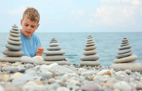 Menino e pilhas de pedra na praia de seixos — Fotografia de Stock