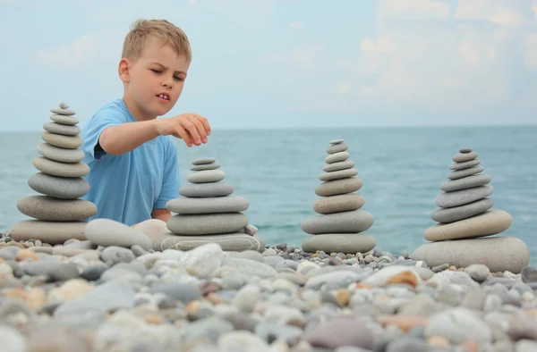 Pojke och sten högar på pebble beach — Stockfoto
