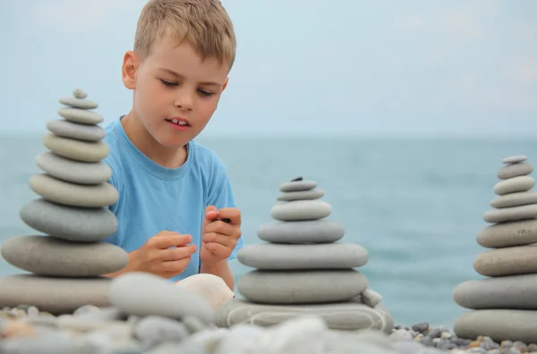 Boy and stone stacks on pebble beach — Stock Photo, Image