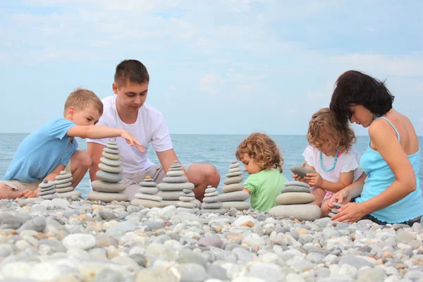 Famiglia costruisce pile di pietra sulla spiaggia di ciottoli — Foto Stock