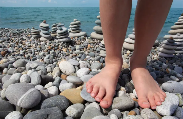 Duas pernas e pilhas de pedra na praia de seixos — Fotografia de Stock