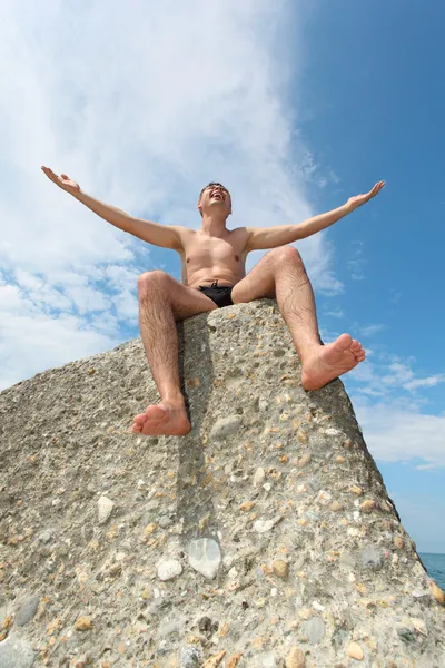 Człowiek siedzi na skale, widok z dołu — Zdjęcie stockowe