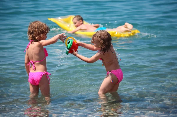 Garçon sur matelas gonflable en mer et deux filles à proximité — Photo