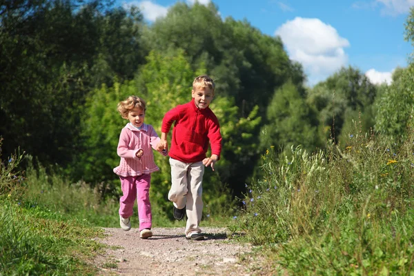 Dos niños corren por el camino en verano —  Fotos de Stock