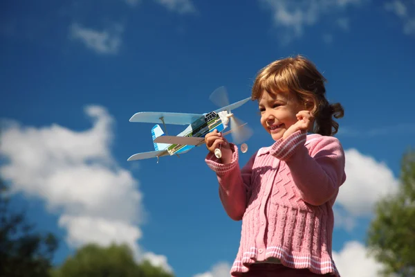 Holčička s letadlo hračka v rukou venkovní proti obloze — Stock fotografie