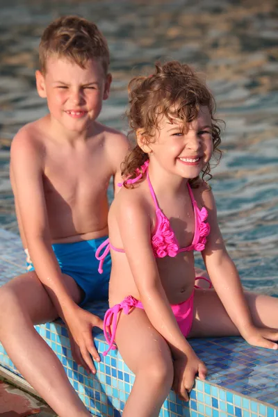 Menino e menina sentar na fronteira da piscina — Fotografia de Stock