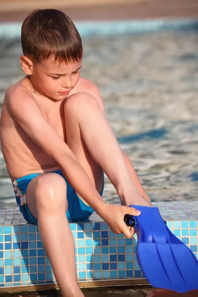 Boy puts on flipperson border of pool — Stock Photo, Image