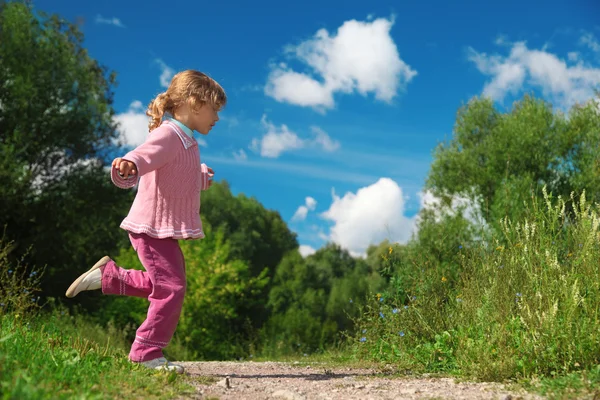 Маленькая девочка бежит по дорожке снаружи — стоковое фото