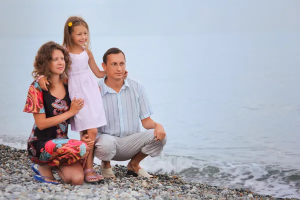 Happy family with little girl on stony beach — Stock Photo, Image