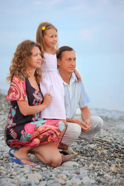 Ευτυχισμένη οικογένεια με μικρό κορίτσι στην πετρώδη παραλία, ψάχνει μακριά — Φωτογραφία Αρχείου