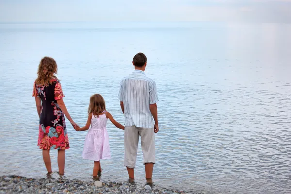 Happy family with little girl standing on beach in evening, stan — Stock Photo, Image