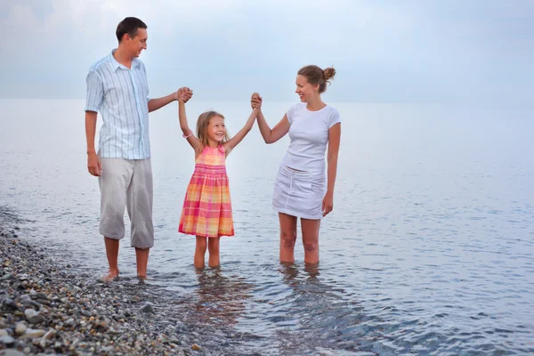 Happy family with little girl walk on beach in evening, having j — Stock Photo, Image