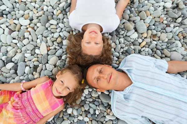 Familia feliz con la niña mintiendo en la playa pedregosa, En cuanto a w — Foto de Stock