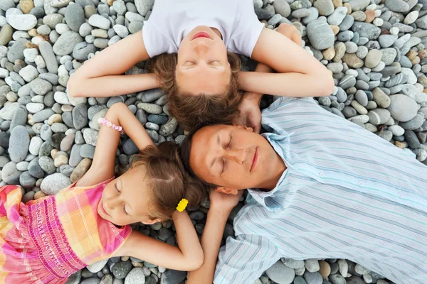 Щаслива сім'я з маленькою дівчинкою, що лежить на кам'янистому пляжі, про — стокове фото