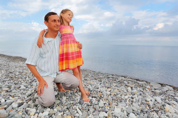 Молодой человек с маленькой девочкой на каменистом пляже — стоковое фото