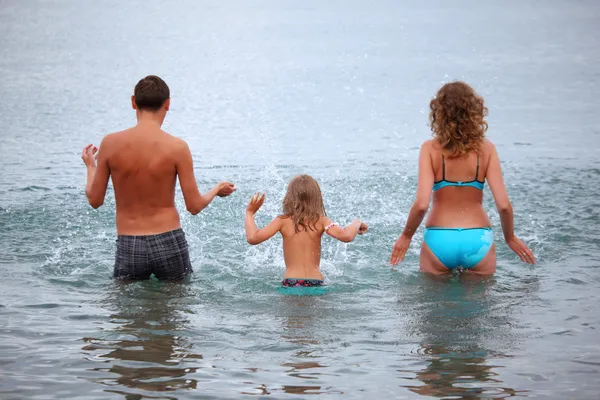 Familia feliz con niña salpica las manos de agua de pie en b —  Fotos de Stock