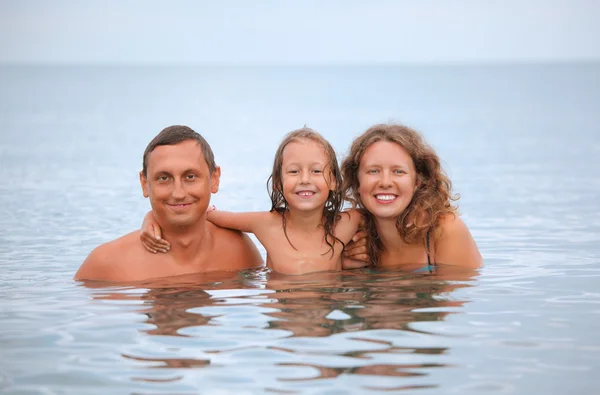 Счастливая семья с маленькой девочкой купается в море — стоковое фото