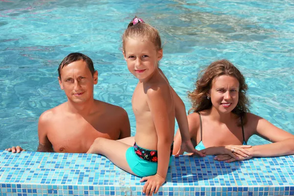 Happy family with little girl bathe in pool, daughter sits near — Stock Photo, Image
