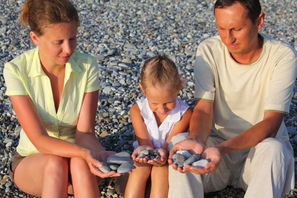 両親と娘の小石の多いビーチに座っています。 — ストック写真
