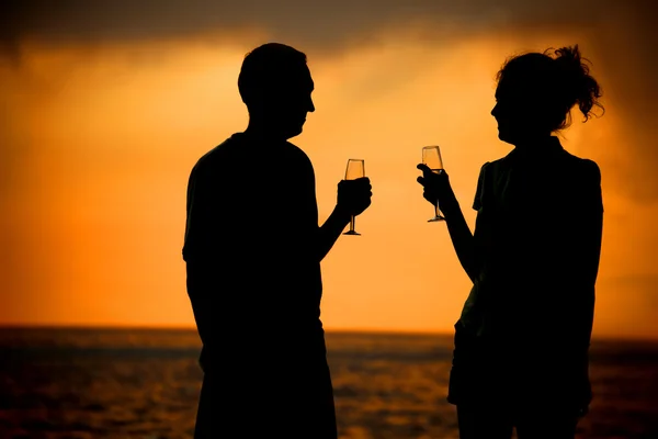 Siluetas de hombre y mujer con gafas en la puesta del sol del mar — Foto de Stock