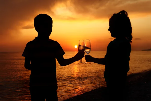 Silhouettes de garçon et fille avec des lunettes sur le coucher du soleil de mer — Photo