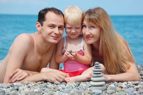 Ouders met kind op Zeekust en piramide van stenen — Stockfoto