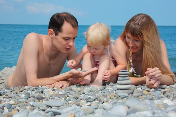 Rodzice z dzieckiem na wybrzeżu Morza i piramida z kamieni — Zdjęcie stockowe