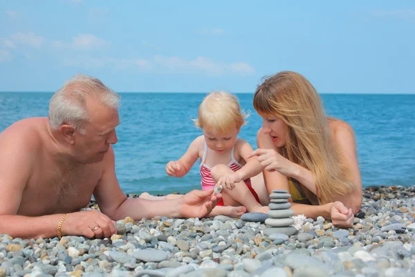 Mother and grandfather with child on sea coast and pyramid of s — Stock Photo, Image