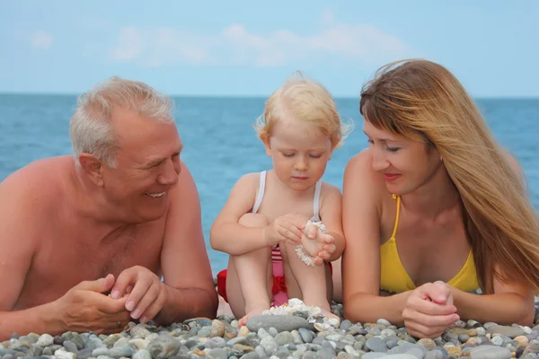 Madre y abuelo con el niño se encuentran en la costa del mar — Foto de Stock