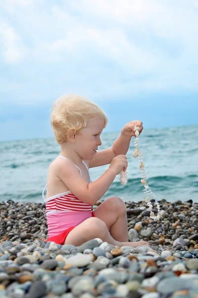 孩子坐在小卵石海滩上 — 图库照片