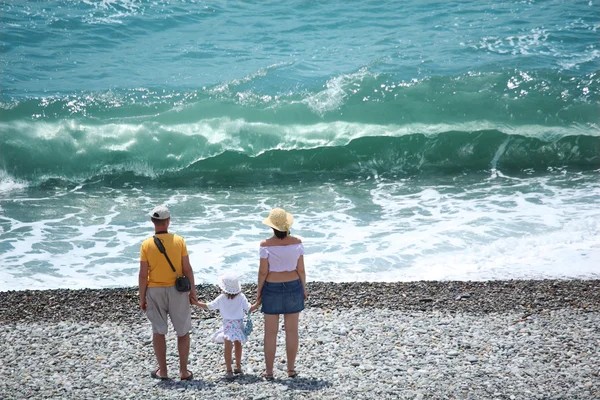 Родители с ребенком стоят на берегу моря, вид сзади — стоковое фото