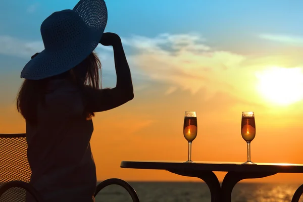Iki bardak ile masanın arkasında Sunset'teki kadın silueti — Stok fotoğraf