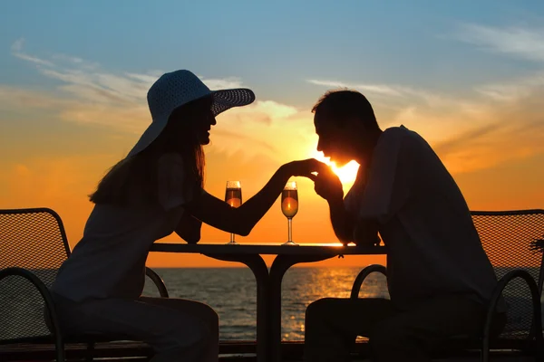 Man kisses hand to woman on sunset behind table outside — Stock Photo, Image