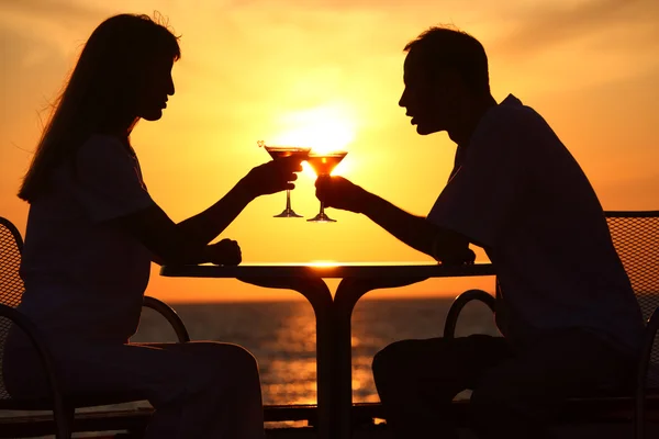 Άνδρας και γυναίκα τσουγκρίζουν τα ποτήρια στο ηλιοβασίλεμα εκτός — Φωτογραφία Αρχείου