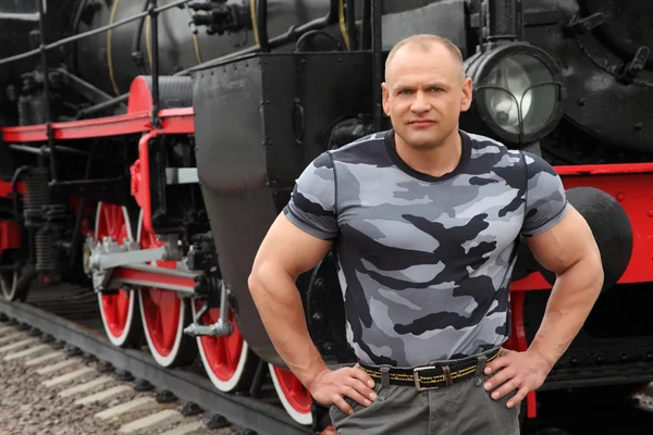 Strong man against locomotive — Stock Photo, Image