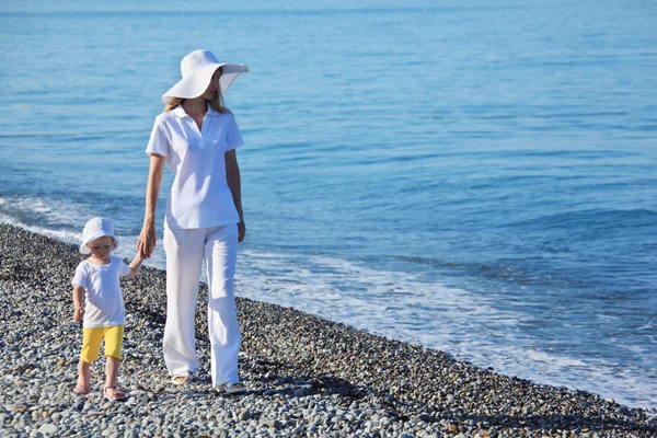 Mother with child walk on edge of sea — Stock Photo, Image