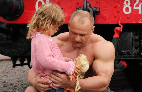 Сильный мужчина без рубашки сидит на железной дороге с маленькой девочкой — стоковое фото