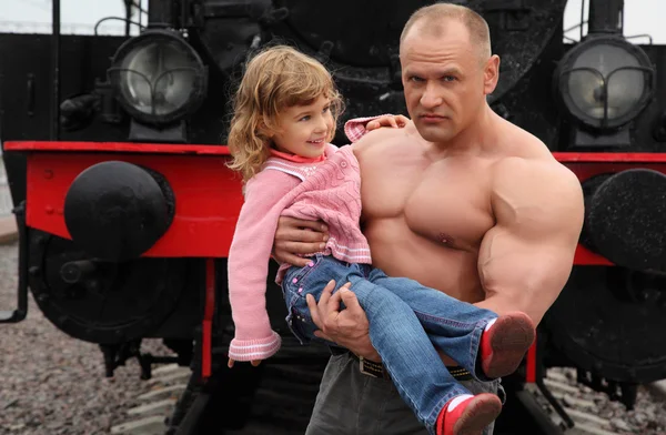Strong shirtless man on railroad with little girl on hands — Stock Photo, Image