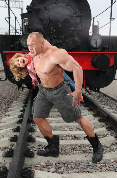 Strong shirtless man saving little girl on railroad — Stock Photo, Image