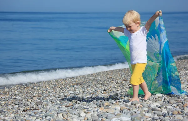 Ребенок с шалью идет на галечный пляж — стоковое фото