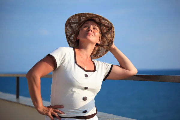 Portrait of middleaged woman in hat on balcony over sea — Stock Photo, Image
