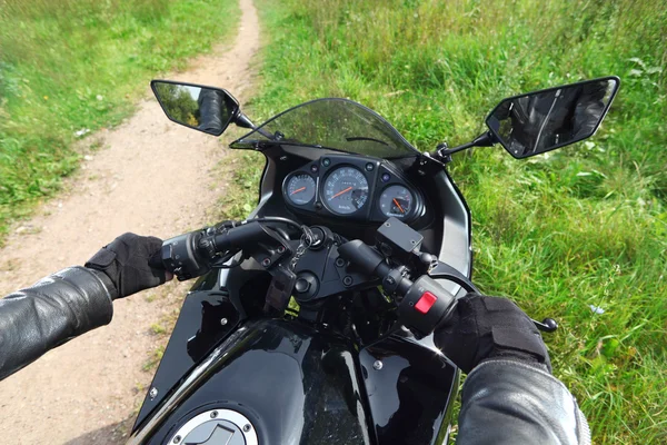 Mãos de motociclista na estrada de campo — Fotografia de Stock